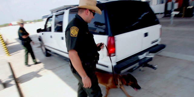 U.S. Border Patrol agents check a car's occupants and use a dog to sniff out drugs at a checkpoint coming into the U.S. outside Laredo, Texas