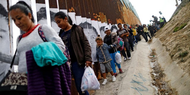 Members of a caravan from Central America walk next to the border fence between Mexico and the U.S., before a gathering in a park and prior to preparations for an asylum request in the U.S., in Tijuana, Mexico April 29, 2018.