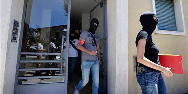 July 16: French hooded police officers leave the building where Bouhlel lived in Nice.