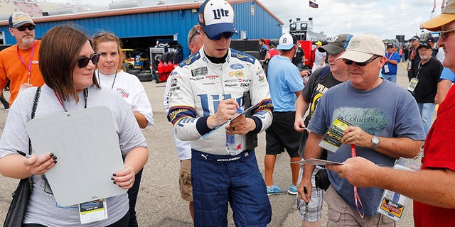 Brad Keselowski signs autographs after practice the NASCAR Cup Series auto race in Brooklyn, Mich., Saturday, Aug. 12, 2017. (AP Photo/Paul Sancya)