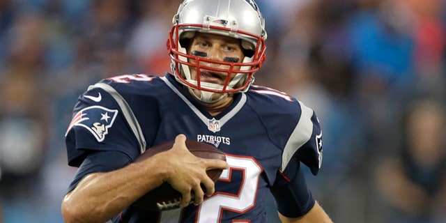Tom Brady scrambles during the first half of a preseason game.
