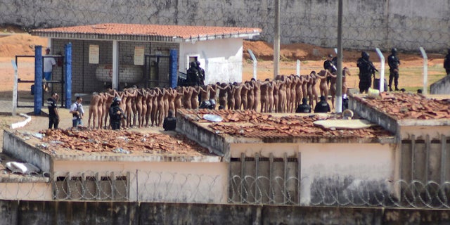 Naked inmates stand in line while surrounded by police after a riot at the Alcacuz prison in Nisia Floresta, Rio Grande do Norte state, Brazil, Sunday, Jan. 15, 2017.