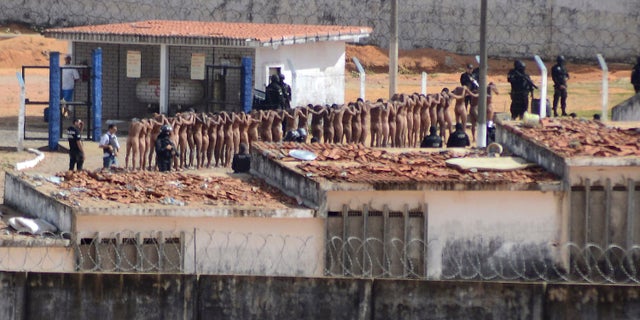 Naked inmates stand in line while surrounded by police after a riot at the Alcacuz prison in Nisia Floresta, Rio Grande do Norte state, Brazil, Sunday, Jan. 15, 2017.
