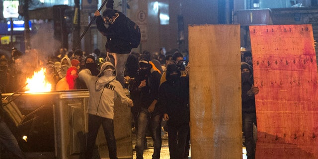 Oct. 7, 2013: Demonstrators with their faces covered throw stones at riot police near the Cinelandia square after a march in support of teachers on strike in Rio de Janeiro, Brazil. Teachers have been on strike demanding better pay for almost two months.