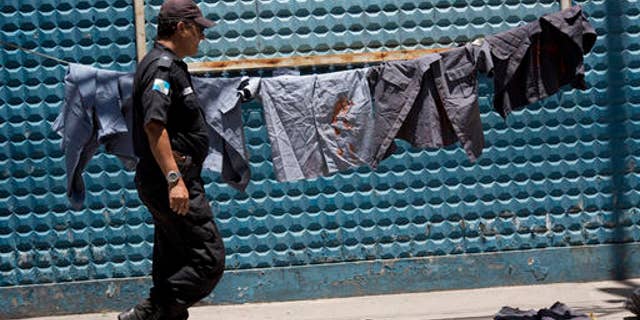 A police officer walks next to uniforms painted with red ink to symbolize blood during a protest in Rio, Brazil, Feb 10, 2017.