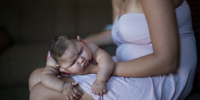 Gleyse Kelly da Silva holds her daughter Maria Giovanna as she sleeps in their house in Recife, Pernambuco state, Brazil, Wednesday, Jan. 27, 2016. Brazilian officials still say they believe there's a sharp increase in cases of microcephaly and strongly suspect the Zika virus, which first appeared in the country last year, is to blame. The concern is strong enough that the U.S. Centers for Disease Control and Prevention this month warned pregnant women to reconsider visits to areas where Zika is present. (AP Photo/Felipe Dana)