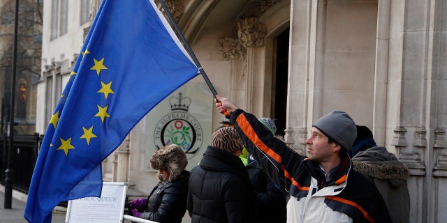 A man waves a European flag in front of the Supreme Court in London, Monday, Dec. 5, 2016.