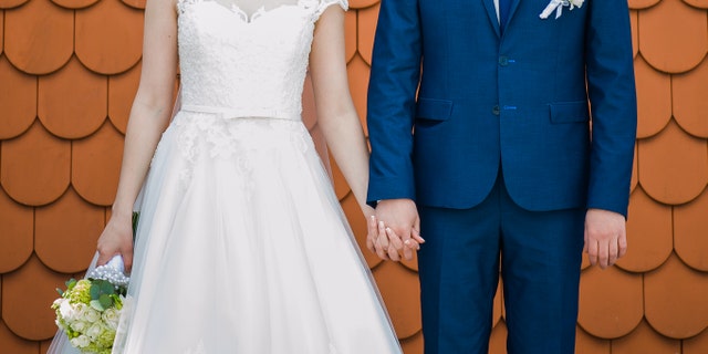 Groom holding bride with wedding bouquet before ceremony near church