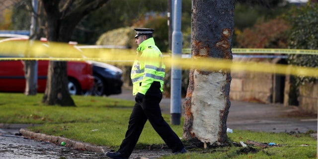 A police officer walks behind crime scene tape at the scene where a stolen car crashed into a tree, leaving 5 people dead, including 3 children, in Leeds, Britain, November 26, 2017.