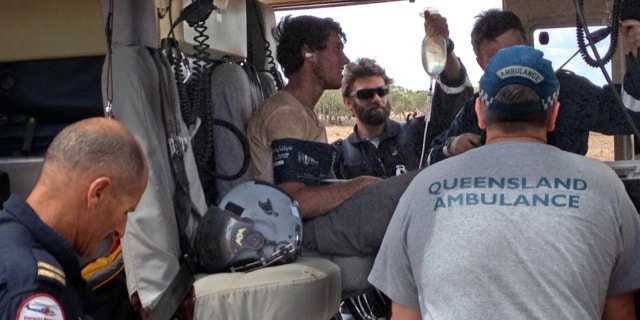 Feb. 15, 2013: British backpacker Sam Derry-Woodhead, second left, sits in a rescue helicopter as he is tended to by ambulance personnel, outside of Longreach, Australia.