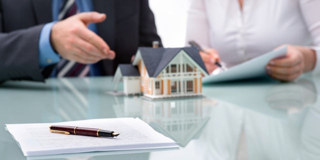 FILE - A banker and a homebuyer discussing a real estate purchase.