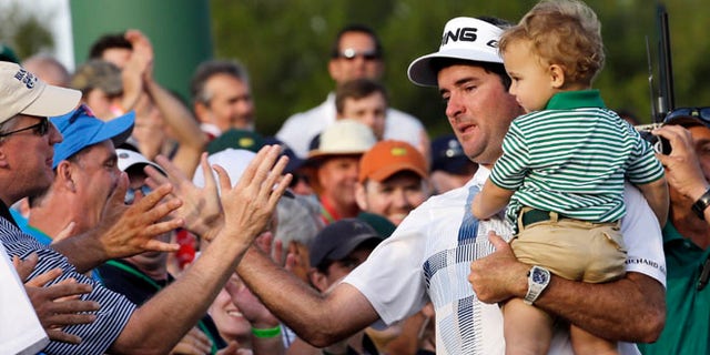 April 13, 2014: Bubba Watson, carrying his son Caleb, is congratulated by spectators after winning the Masters golf tournament in Augusta, Ga.