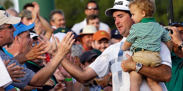April 13, 2014: Bubba Watson, carrying his son Caleb, is congratulated by spectators after winning the Masters golf tournament in Augusta, Ga.