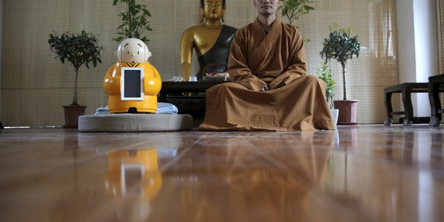 Master Xianfan sits next to robot Xian'er as he poses for photograph at Longquan Buddhist temple on the outskirts of Beijing, April 20, 2016. (REUTERS/Kim Kyung-Hoon)