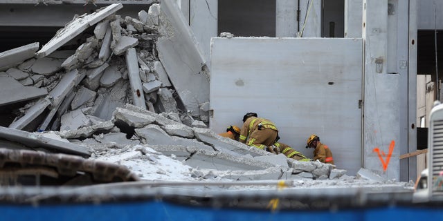 DORAL, FL - OCTOBER 10: Miami-Dade Rescue workers prepare to pull a body out of the rubble of a four-story parking garage that was under construction and collapsed at the Miami Dade College?s West Campus on October 10, 2012 in Doral, Florida. Early reports indicate that one person was killed in the collapse, at least seven people injured and one person may still be trapped in the rubble. (Photo by Joe Raedle/Getty Images)