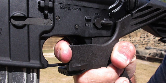 Shooting instructor Frankie McRae illustrates the grip on an AR-15 rifle fitted with a "bump stock" at his 37 PSR Gun Club in Bunnlevel, N.C., on Wednesday, Oct. 4, 2017. The stock uses the recoil of the semiautomatic rifle to let the finger "bump" the trigger, making it different from a fully automatic machine gun, which are illegal for most civilians to own. (AP Photo/Allen G. Breed)