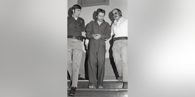In this 1977 photo serial killer Ted Bundy, center, is escorted out of court in Pitkin County, Colo. The Glenwood Springs Post-Independent discovered the 40-year-old photo of Bundy, along with others, that had been locked in an old safe in the newsroom, which a local locksmith volunteered to open. The photos show Bundy in custody in 1977, the year he escaped from local law enforcement twice while awaiting a murder trial. (Glenwood Springs Post Independent via AP)