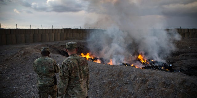 FILE -- U.S. Army soldiers watch garbage burn in a burn-pit at Forward Operating Base Azzizulah in Maiwand District, Kandahar Province, Afghanistan, February 4, 2013. REUTERS/Andrew Burton