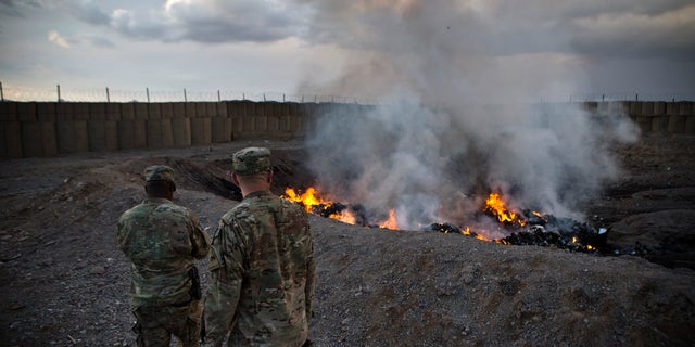 U.S. Army soldiers watch garbage burn in a burn pit at Forward Operating Base Azzizulah in Maiwand District, Kandahar Province, Afghanistan, in February 2013. (REUTERS/Andrew Burton)