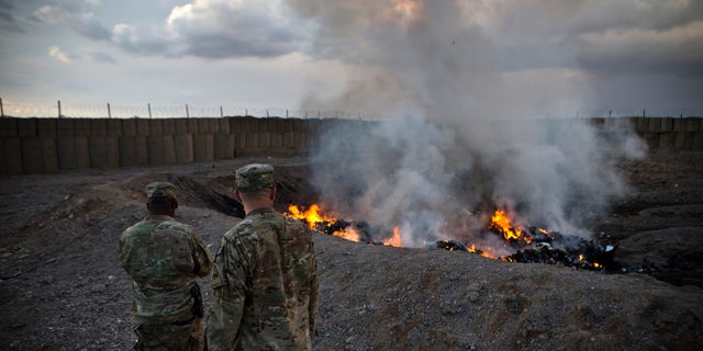 U.S. Army soldiers watch a burning crater at Forward Operating Base Azizullah in Maiwand District, Kandahar Province, Afghanistan, February 4, 2013.