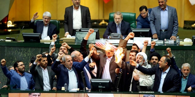 Iranian lawmakers celebrate as they burn a paper American flag.