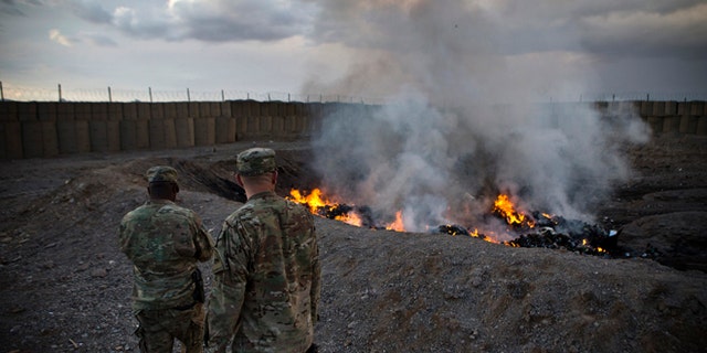 U.S. Army soldiers watch garbage burn in a burn-pit on Feb. 4, 2013 at Forward Operating Base Azzizulah in the Kandahar Province of Afghanistan.