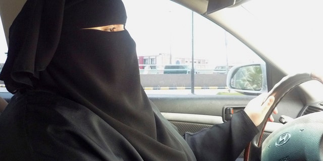 A woman wearing a burka, behind the wheel of a car.
