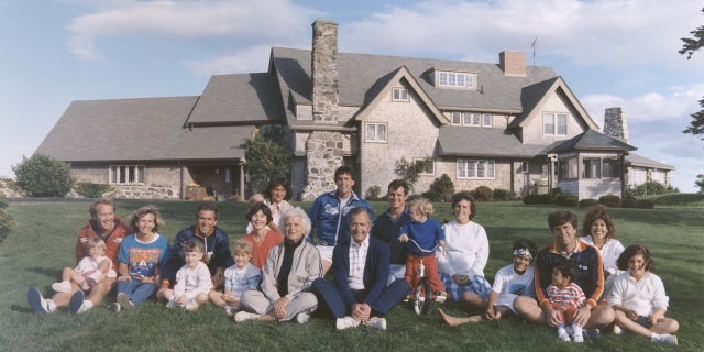 Portrait of the Bush family sitting in front of their home in Kennebunkport, Maine. BACK ROW: Maragret Bush (Marvin's wife), holding daughter Marshall, Marvin Bush, Bill LeBlond (Doro's Husband). FRONT ROW: Neil Bush holding son Pierce, Sharon (Neil's wife), George W. Bush holding daughter Barbara Bush, George Bush, Sam LeBlond (Doro's son), Doro Bush LeBlond, George P.