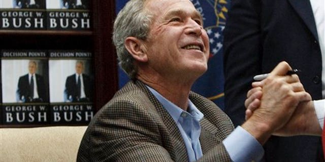 Former President George W. Bush shakes hands with a man after autographing a copy of his memoir Friday, Nov. 19, 2010, in Sandy, Utah. More than 1,000 people were lined up waiting for an autographed copy of the former president's memoir, "Decision Points."