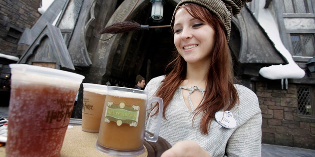 This June 9, 2010 file photo shows Erin Wuchte as she serves up Butterbeer to guests at The Wizarding World of Harry Potter at Universal Orlando theme park in Orlando, Fla. Harry has conjured all the magic Universal expected, and then some. In the quarter after the attraction opened, crowds at Universal parks swelled by 36 percent over the same stretch last year, while attendance at Disney's Orlando parks stayed roughly the same. (AP Photo/John Raoux, FILE)