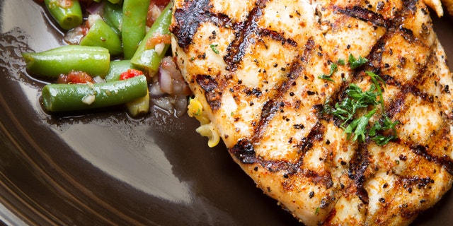 Healthy grilled chicken on a plate with fresh cut french fried potatoes and green beansq. Chicken breast is garnished with parsley