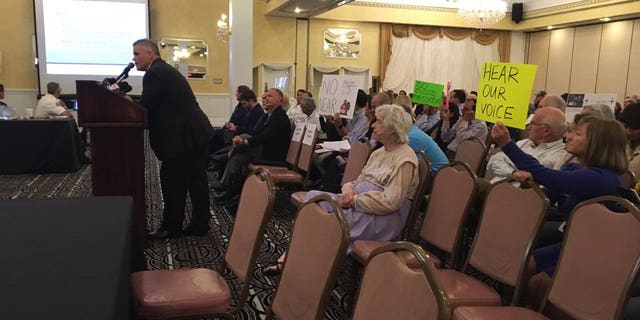 Opponents of the "guntry club" brought signs to the town hall meeting.