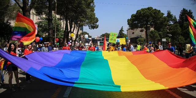 Participants of the Gay Pride Parade hold a rainbow flag during a rally held without any disturbances, while the country's political opposition prepared for an unrelated national protest in the capital, in Tirana, Albania, in 2017.