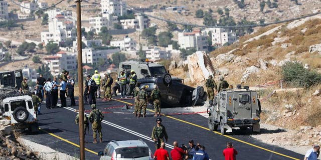 FILE - In this Friday, July 1, 2016, file photo, Israeli soldiers secure the scene of a car crash after a shooting attack near Hebron, West Bank, Friday, July 1, 2016. A few years ago, Islam al-Bayed spent seven months in an Israeli prison for allegedly throwing stones at Israeli troops. Now, the 26-year-old Palestinian man has become an unlikely symbol of coexistence after rescuing an Israeli family whose car crashed following a deadly roadside shooting by Palestinian militants in the West Bank. (AP Photo/Nasser Shiyoukhi)