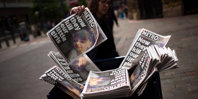 A woman grabs a newspaper reporting the news of a terror attack at Manchester Arena, May 24, 2017.