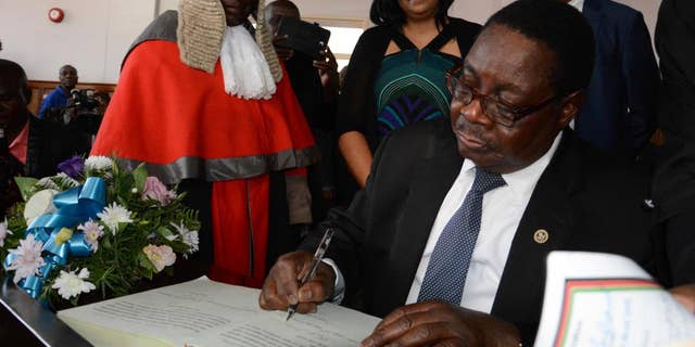 Newly elected Malawian president Peter Mutharika signs the oath book after he was sworn in, at the High Court in Blantyre, Malawi, Saturday May 31, 2014. Malawi's election commission has declared opposition leader Mutharika to be the winner of an election that was marred by scattered unrest and complaints from the president and others that the vote was rigged. (AP Photo/Thoko Chikondi)