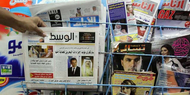 File - In this Tuesday, April 5, 2011, file photo, a man picks up a copy of Al Wasat newspaper at a newsstand in Hamad Town, Bahrain. Bahraini authorities have ordered the independent newspaper to stop publishing online Monday and say a city hall was set ablaze during clashes between opposition protesters and police. The suspension of Al-Wasat’s online operations followed a spike in anti-government protests led by the country’s Shiite majority that began Saturday.  (AP Photo/Hasan Jamali, File)