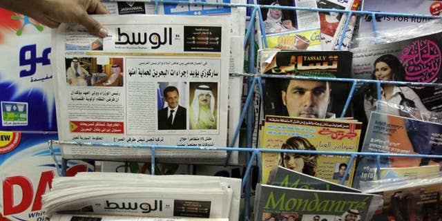 File - In this Tuesday, April 5, 2011, file photo, a man picks up a copy of Al Wasat newspaper at a newsstand in Hamad Town, Bahrain. Bahraini authorities have ordered the independent newspaper to stop publishing online Monday and say a city hall was set ablaze during clashes between opposition protesters and police. The suspension of Al-Wasat’s online operations followed a spike in anti-government protests led by the country’s Shiite majority that began Saturday. (AP Photo/Hasan Jamali, File)