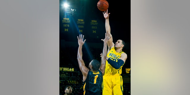 Michigan forward Jordan Morgan, right, takes a shot over Iowa forward Melsahn Basabe (1) in the first half of an NCAA college basketball game in Ann Arbor, Mich., Wednesday, Jan. 22, 2014. (AP Photo/Tony Ding)