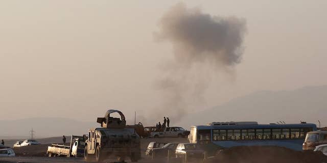 FILE - In this Aug. 8, 2014 file photo, an armored vehicle belonging to Kurdish Peshmerga fighters rushes to a bombing site as smoke rises after airstrikes targeting Islamic State militants near the Khazer checkpoint outside of the city of Irbil in northern Iraq. The airstrikes were launched outside the Kurdish regional capital Irbil, and marked the first time U.S. forces have directly targeted the extremist Islamic State group, which controls large areas of Syria and Iraq. The death last week of a Canadian soldier, reportedly killed by friendly fire from Kurdish troops near the northern village of Bashiq, has put the spotlight once again on the dangers that U.S. troops could face in Iraq. (AP Photo/ Khalid Mohammed, File)