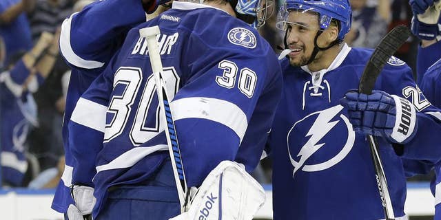 Tampa Bay Lightning goalie Ben Bishop (30) celebrates with right wing J.T. Brown (23) after the team defeated the Montreal Canadiens 4-1 during Game 6 of a second-round NHL Stanley Cup hockey playoff series Tuesday, May 12, 2015, in Tampa, Fla. (AP Photo/Chris O'Meara)