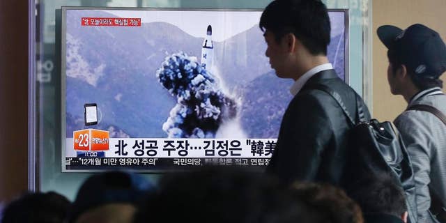 FILE - In this April 24, 2016 file photo, a man walks by as people watch a TV news program showing an image published earlier in the day in North Korea's Rodong Sinmun newspaper of North Korea's ballistic missile that the North claimed to have launched from underwater, at Seoul Railway station in Seoul, South Korea. With Donald Trump getting ready to become president, North Korea is talking about launching an ICBM and Washington officials are saying they will shoot down anything that threatens the territory of the U.S. or its allies. (AP Photo/Ahn Young-joon, File)