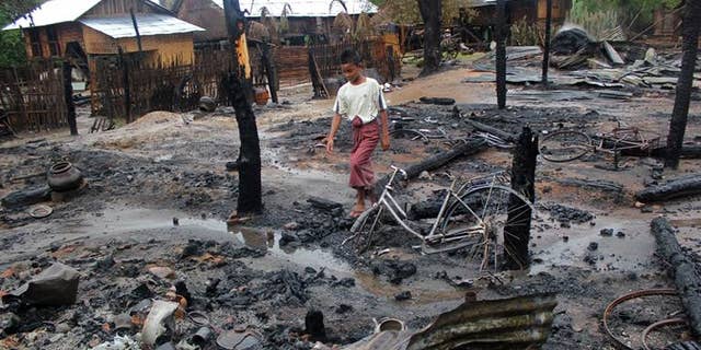 A Muslim boy walks through the charred remains of houses in Htan Gone village on August 26, 2013, after some 1,000 anti-Muslim rioters rampaged through villages in Kanbalu township in Myanmar.