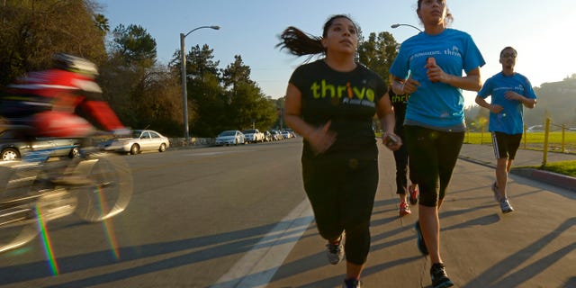 Zendi Solano, center, trains with running club members Rian Barrett.