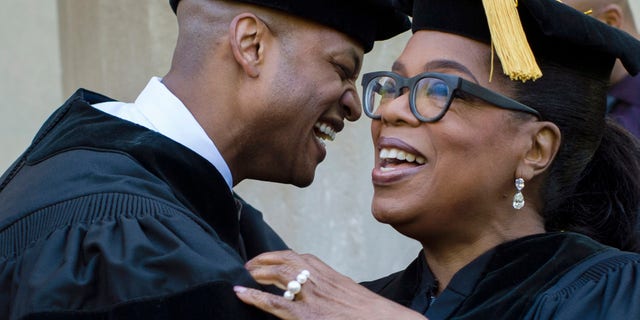 In this photo provided by Skidmore College, author Wes Moore embraces Oprah Winfrey at Skidmore College's 106th Commencement, Saturday, May 20, 2017 at the Saratoga Performing Arts Center, in Saratoga Springs, N.Y. The author, actress and former talk show host spoke at the graduation. (Erin Covey/Skidmore College via AP)