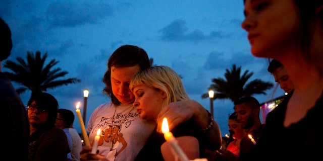 In this June 13, 2016, file photo, Lucinda Rex, right, and Clarity Thorne embrace during a candlelight vigil downtown for the victims of a mass shooting at the Pulse nightclub in Orlando, Fla.