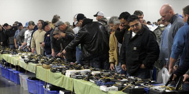 Dec. 22, 2012: People look over a table of handguns for sale at a gun show in Kansas City, Missouri.