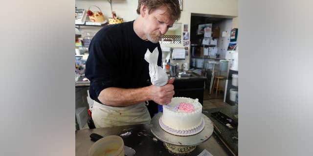 FILE - In this March 10, 2014, file photo, Masterpiece Cakeshop owner Jack Phillips decorates a cake inside his store in Lakewood, Colo.