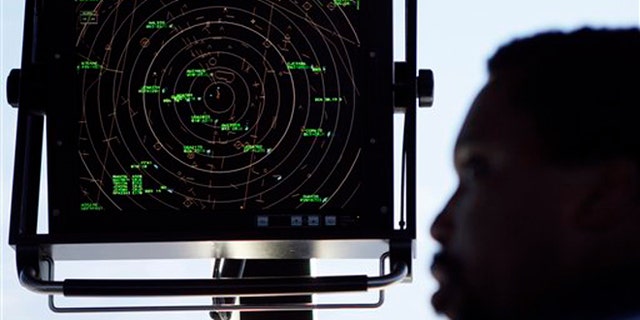 In this Sept. 18, 2008, file photo an air traffic controller stands beneath a radar screen in the control tower at Washington's Reagan National Airport.