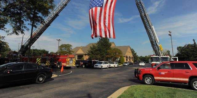A large American flag is unfurled by Sterling Heights and Washington Twp. Fire Departments as mourners begin to arrive for visitation for Detroit Police officer Ken Steil in Sterling Heights, Mich., Wednesday Sept. 21, 2016.  Steil died unexpectedly Saturday of a blood clot, five days after being shot in the shoulder.  (Steve Perez/Detroit News via AP)